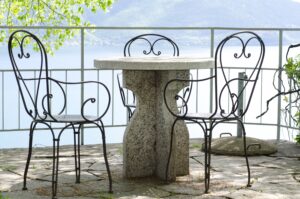 A patio with a stone table and chairs with the view over a lake